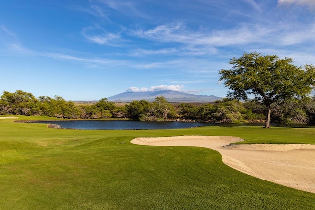 view of home's community with view of golf course, a yard, and a water and mountain view