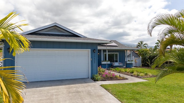 view of front of home with concrete driveway, an attached garage, board and batten siding, a front yard, and roof mounted solar panels