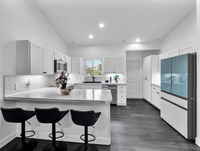 kitchen featuring stainless steel appliances, a sink, a peninsula, and a kitchen bar