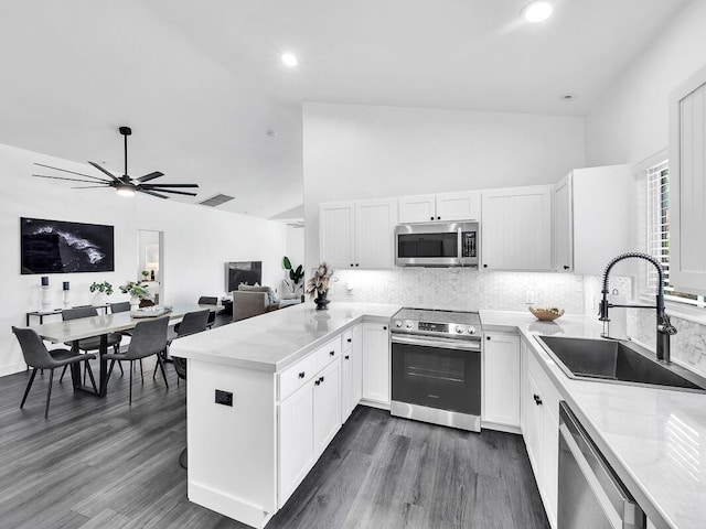 kitchen with a peninsula, white cabinetry, appliances with stainless steel finishes, and a sink