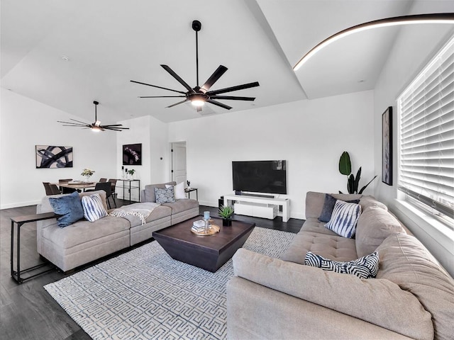 living room with arched walkways, dark wood-style flooring, lofted ceiling, ceiling fan, and baseboards