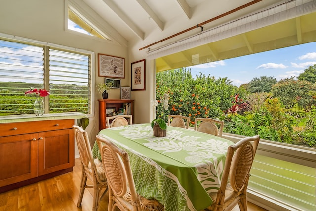 dining area with vaulted ceiling with beams and light wood-type flooring