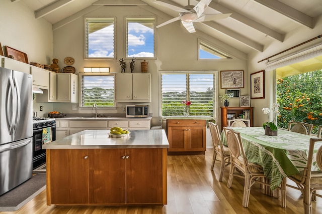kitchen featuring a sink, stainless steel appliances, beamed ceiling, and light wood finished floors