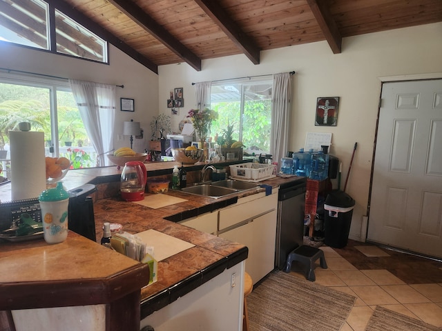 kitchen with white cabinets, dishwashing machine, vaulted ceiling with beams, a sink, and light tile patterned flooring