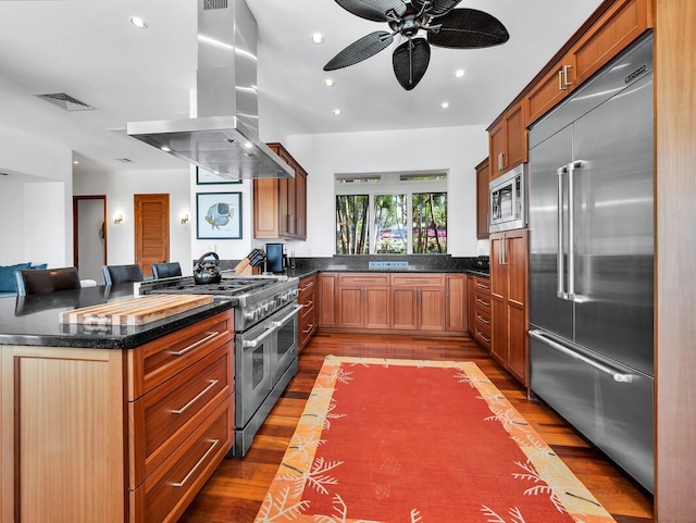 kitchen featuring visible vents, wood finished floors, range hood, recessed lighting, and built in appliances