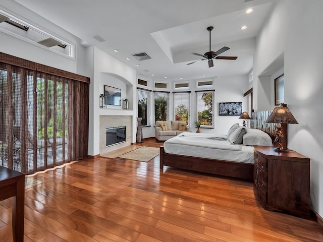 bedroom featuring hardwood / wood-style floors, multiple windows, a fireplace, and visible vents