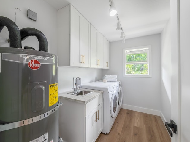 clothes washing area with baseboards, washing machine and dryer, light wood-type flooring, water heater, and a sink