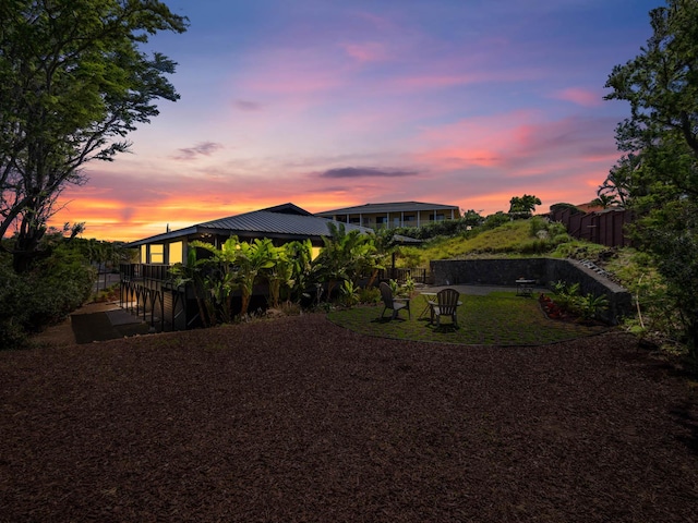 back of property at dusk featuring fence, driveway, and metal roof
