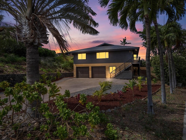 view of front of property featuring stucco siding, driveway, an attached garage, and stairs