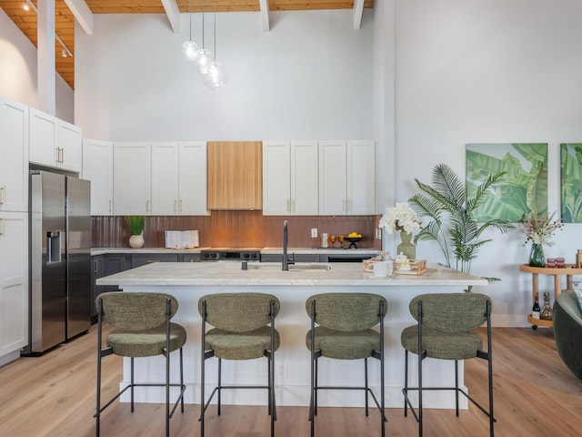 kitchen with a sink, stainless steel fridge, a high ceiling, and beam ceiling