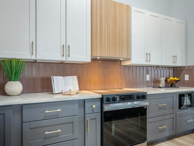 kitchen featuring built in microwave, tasteful backsplash, range with electric stovetop, and gray cabinets