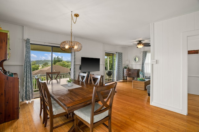 dining space with light wood-style flooring and ceiling fan with notable chandelier