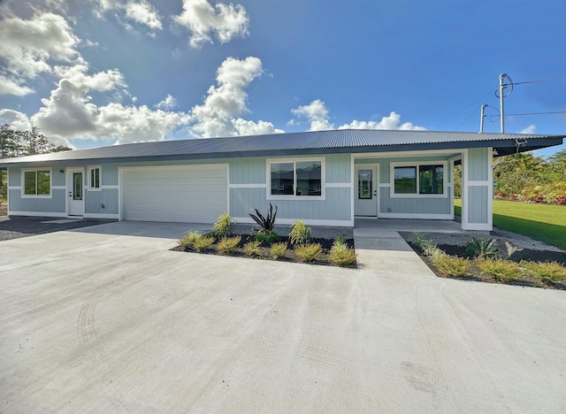 single story home with a porch, an attached garage, metal roof, and concrete driveway