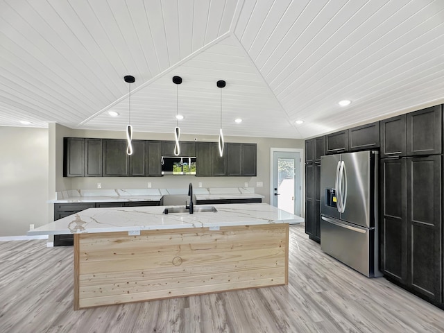 kitchen with decorative light fixtures, an island with sink, appliances with stainless steel finishes, light wood-style floors, and a sink