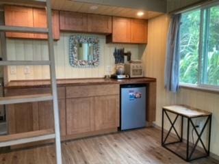 bar featuring fridge, a bar, and light wood finished floors