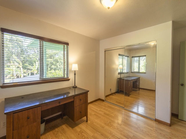 unfurnished office featuring baseboards and light wood finished floors