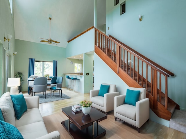 living room with ceiling fan, a high ceiling, stairway, and wood finished floors