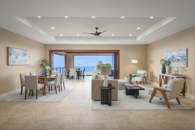 living area featuring a tray ceiling, recessed lighting, and baseboards