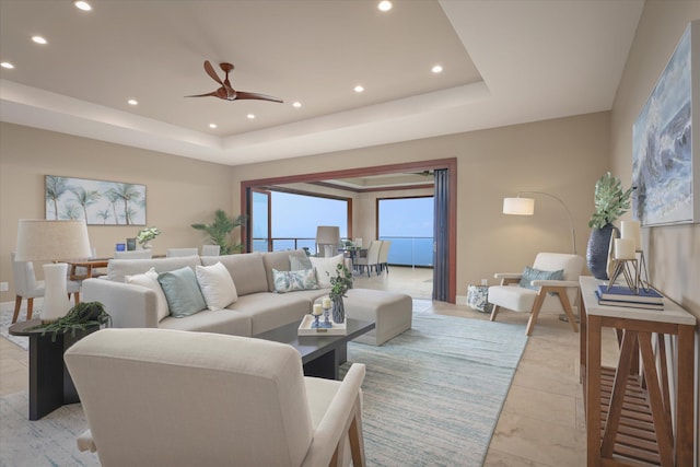 living room with a tray ceiling, ceiling fan, and recessed lighting