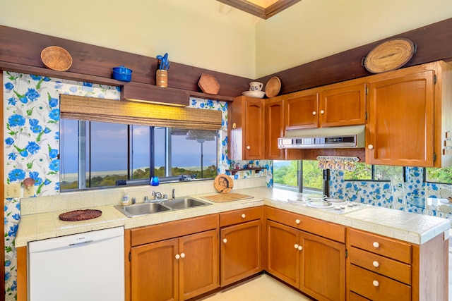 kitchen with white appliances, under cabinet range hood, light countertops, and a sink