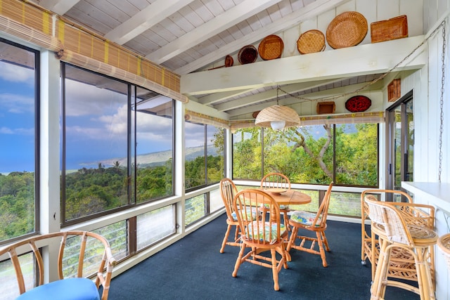 sunroom with lofted ceiling with beams, a healthy amount of sunlight, and wood ceiling