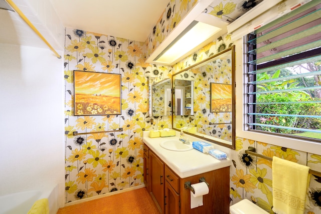 bathroom with vanity, toilet, and wallpapered walls