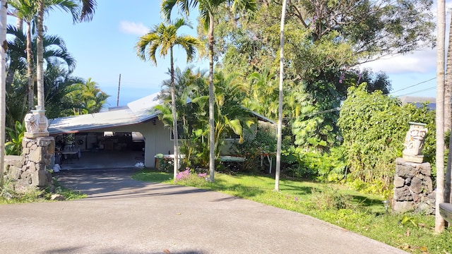 exterior space featuring aphalt driveway, a carport, and a yard