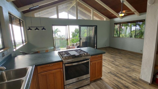 kitchen featuring brown cabinets, a sink, dark countertops, gas stove, and vaulted ceiling with beams