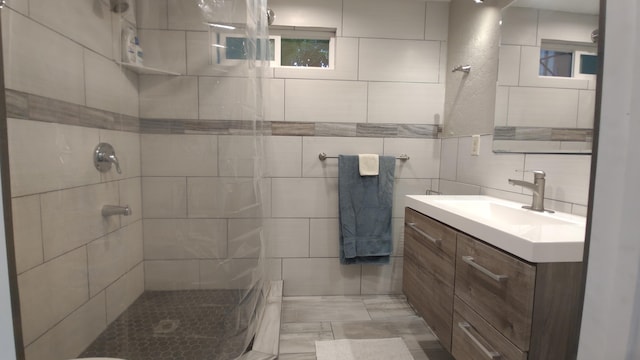 bathroom featuring decorative backsplash, tiled shower, tile walls, and vanity