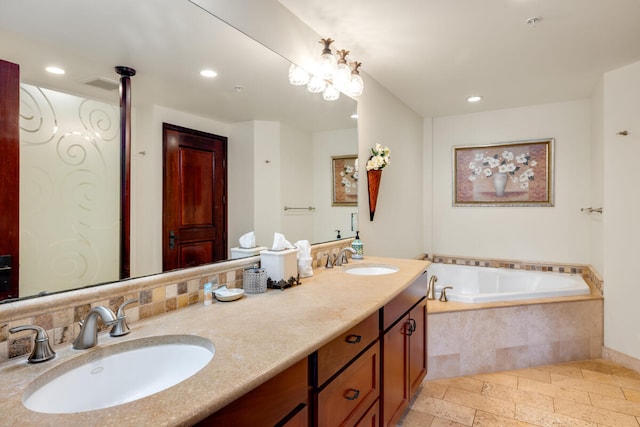 full bath featuring a sink, stone tile floors, and recessed lighting