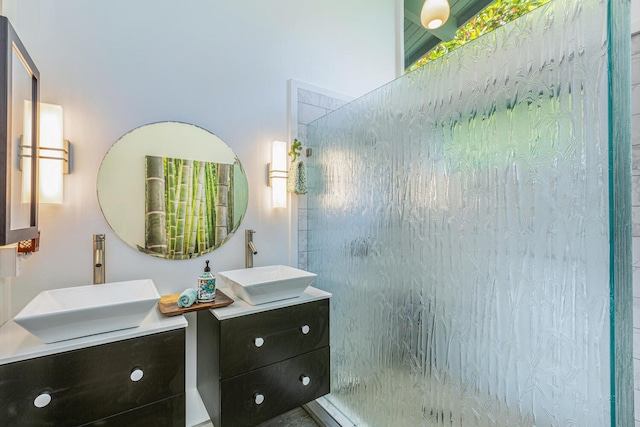 full bathroom featuring two vanities, tiled shower, and a sink