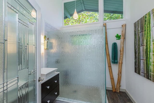 full bathroom with a healthy amount of sunlight, tiled shower, vanity, and wood finished floors