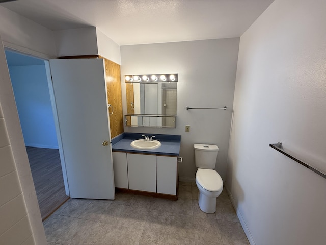 bathroom with baseboards, toilet, and vanity