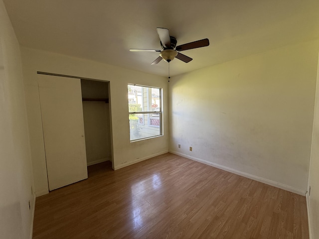 unfurnished bedroom with a closet, baseboards, wood finished floors, and a ceiling fan