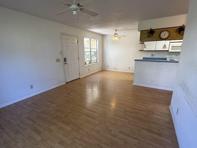 unfurnished living room featuring baseboards, wood finished floors, and a ceiling fan