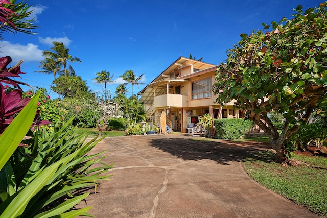 view of front of house with a carport, concrete driveway, and a balcony