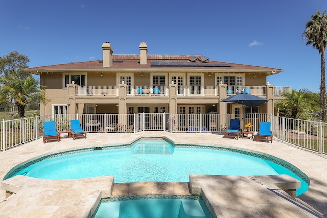 view of swimming pool featuring french doors, fence, a pool with connected hot tub, and a patio area