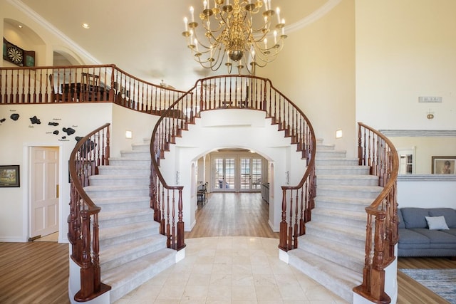 stairway with french doors, arched walkways, a high ceiling, crown molding, and baseboards