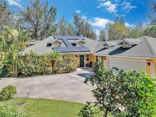 view of front of property featuring driveway, roof with shingles, solar panels, and an attached garage