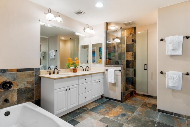 full bath with a sink, visible vents, stone tile flooring, and a shower stall