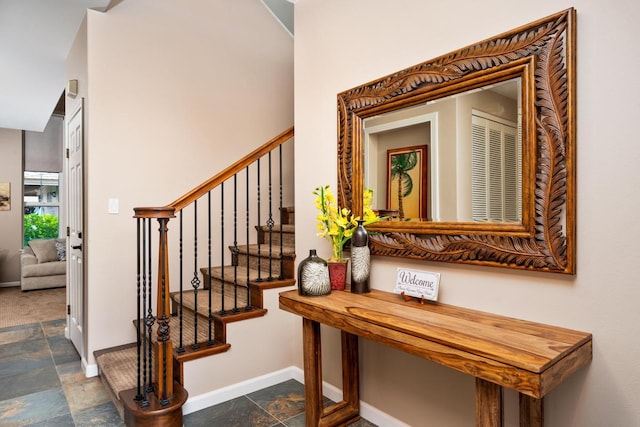 staircase with baseboards and stone tile flooring