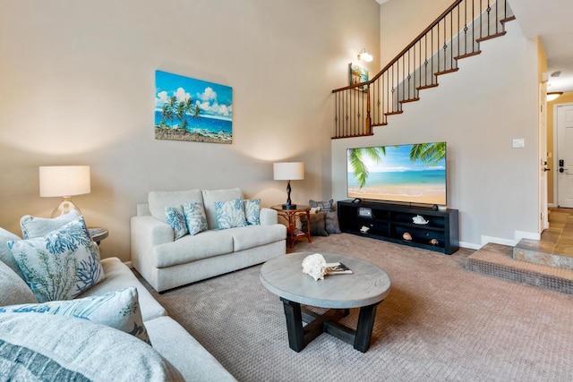 carpeted living room featuring stairway, baseboards, and a towering ceiling