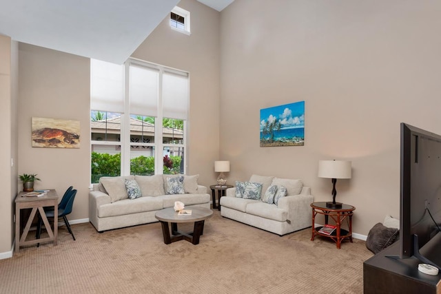 living area featuring baseboards, a towering ceiling, and light carpet