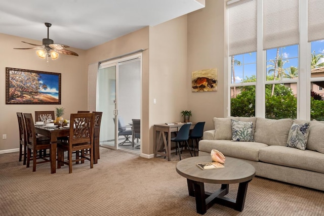 dining room featuring light colored carpet, baseboards, and ceiling fan