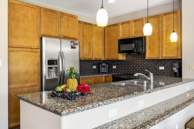 kitchen featuring a sink, stainless steel refrigerator with ice dispenser, dark stone countertops, and black microwave