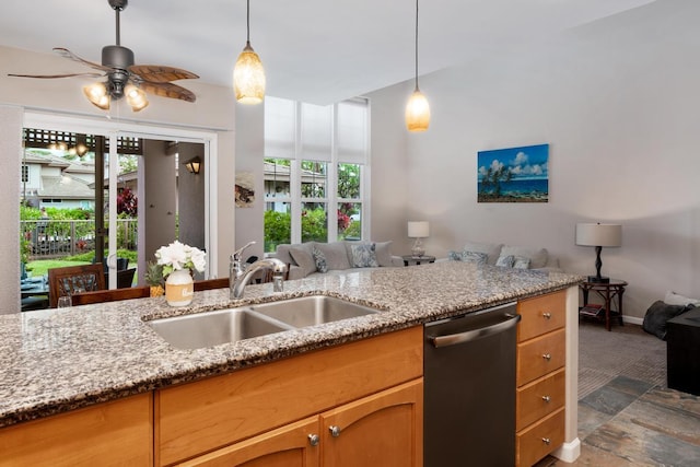 kitchen featuring light stone countertops, open floor plan, dishwasher, a ceiling fan, and a sink