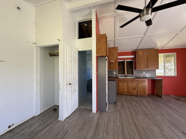 kitchen featuring brown cabinetry, a ceiling fan, dark wood finished floors, a sink, and backsplash