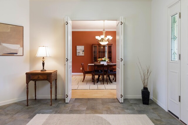 foyer entrance featuring baseboards, a notable chandelier, and ornamental molding