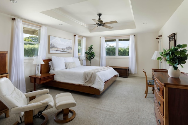 bedroom featuring a ceiling fan, a tray ceiling, crown molding, and light colored carpet