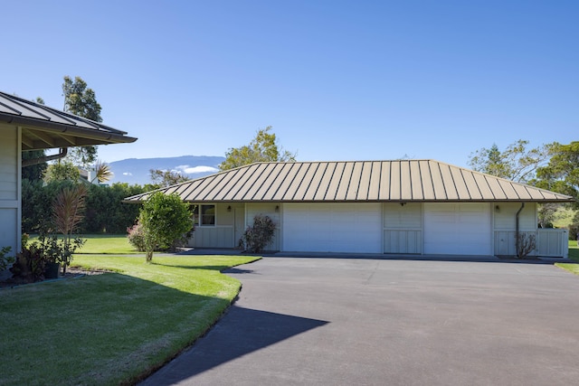 view of front facade with an attached garage, driveway, metal roof, a front lawn, and a standing seam roof